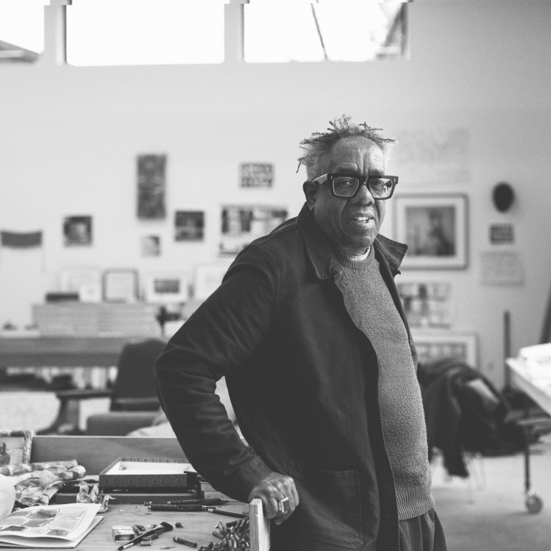 Photograph of a black man with glasses in an art studio