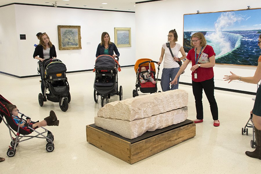 Parents with children in strollers look at art
