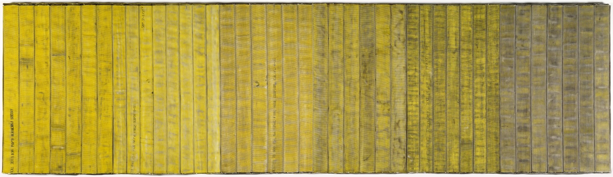 This large-scale wall-mounted sculpture features forty-one sections of fire hose of equal size laid vertically side-by-side. From left to right, the sections of fire hose progressively appear more worn. The dominant color of the fabric gradually transitions from yellow to tones of gray. Some sections of the fire hose are stamped with black letters spelling out the original manufacturer specifications.