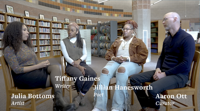 Screenshot of a video of three women and one man sitting in a library talking 