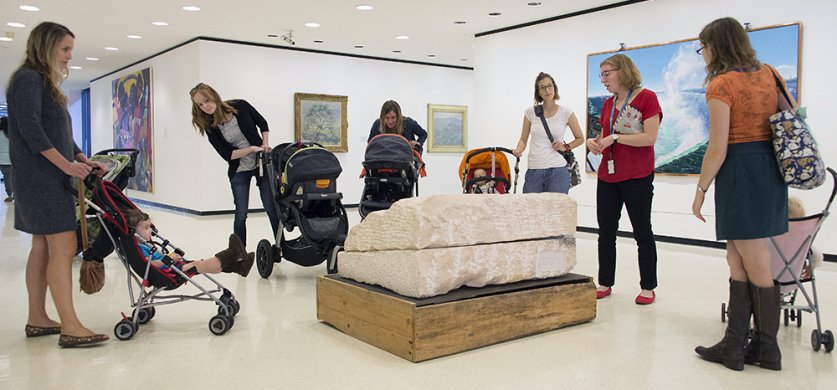 Parents with babies in strollers looking at art