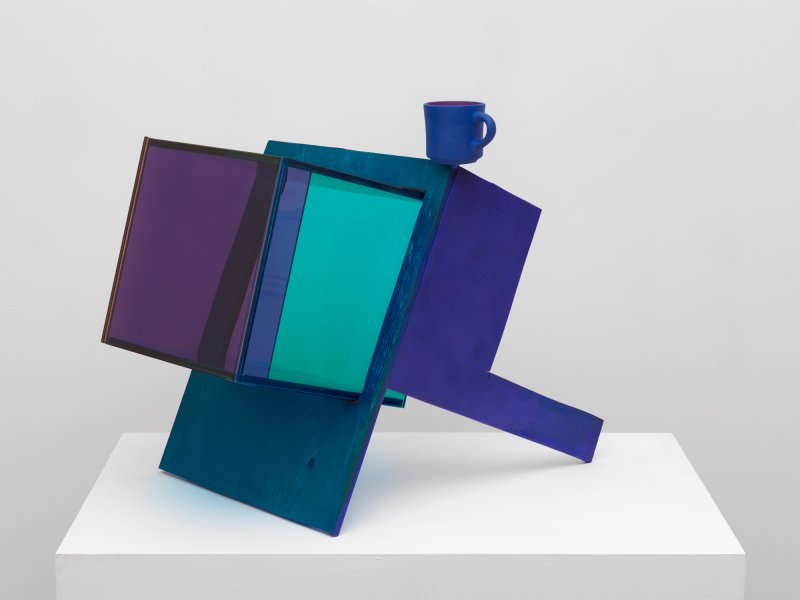 A sculpture of a purple and blue box with light blue plexiglass and a blue teacup on top