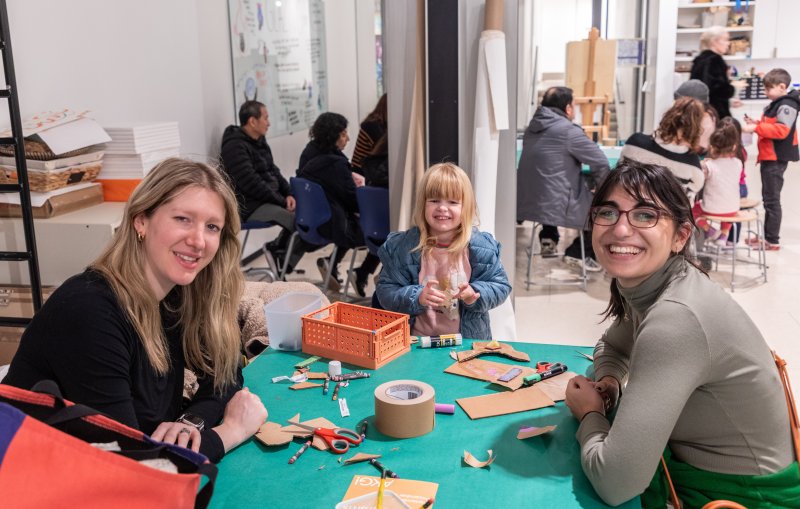 Two women and a young girl smiling for the camera at an arts and crafts table