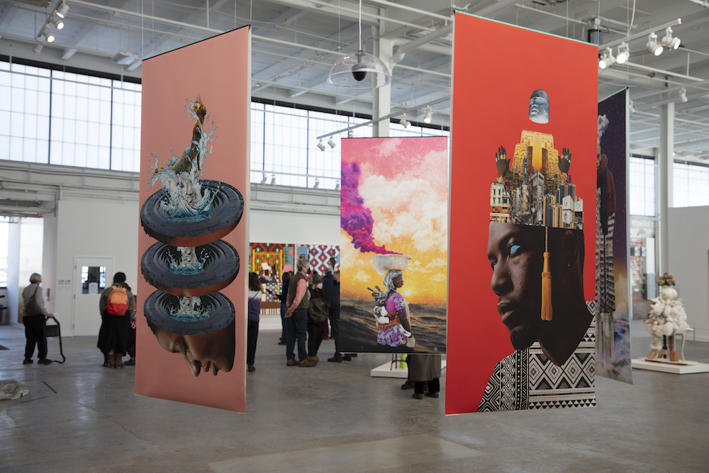 Bright, surreal collages hang in a circle in the middle of an industrial exhibition space