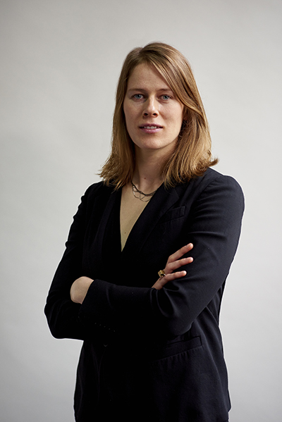A white woman with shoulder length hair wearing a black sweater with her arms crossed across her chest