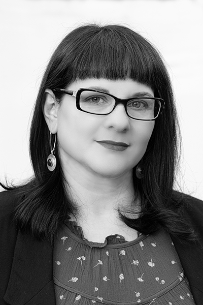 Black and white photo of a white woman with dark hair and glasses