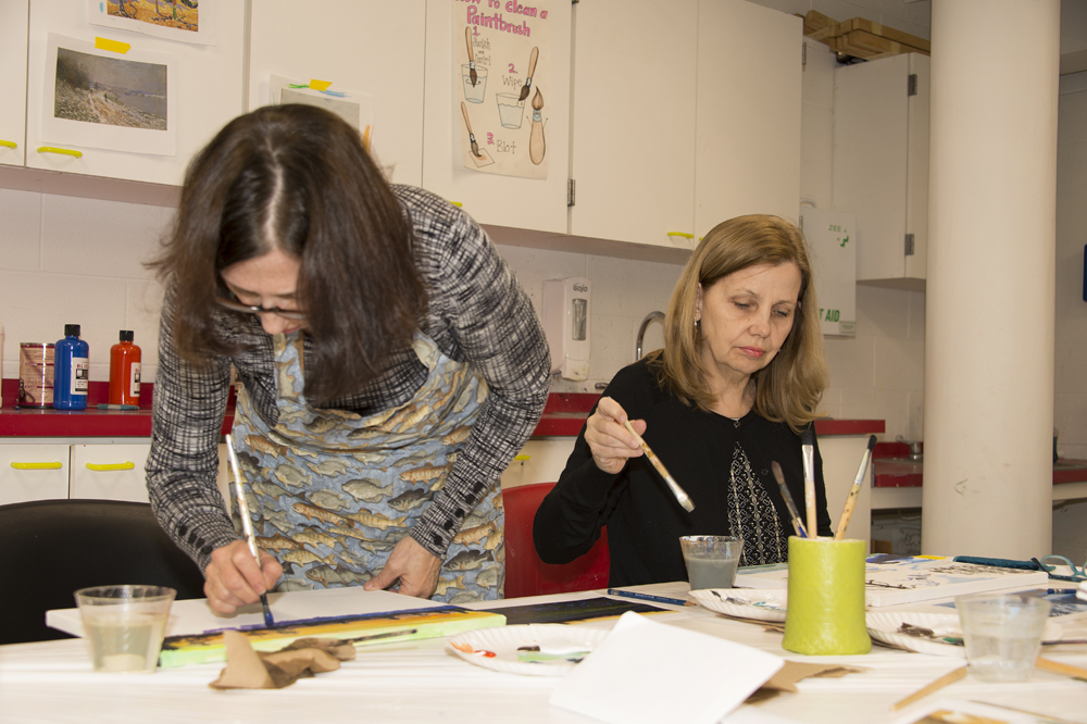 Women working on a painting at a studio art workshop