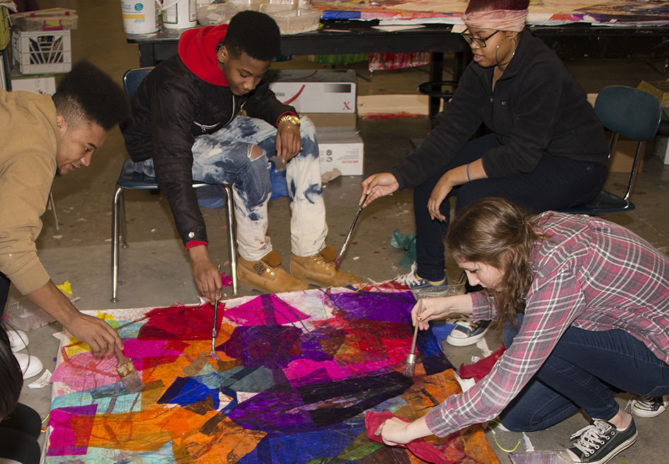Image of students working on a brightly colored artwork