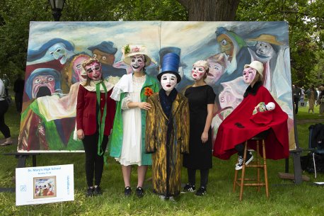 A group of kids dressed in elaborate costumes and masks in front of a painted backdrop