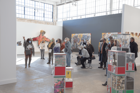 A group of people exploring an exhibition surrounded by paintings and sculptures