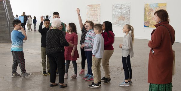 Two adults with a group of kids looking at art