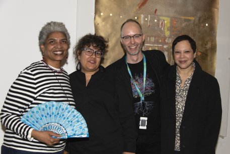 Two African American women, a white man, and a Latinx woman standing in front of a painting