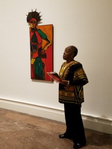 An African American woman talking in front of a painting