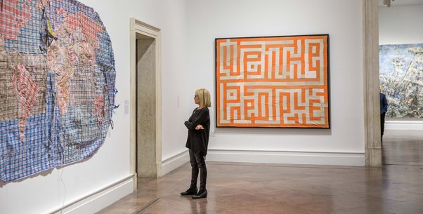 A woman looking at large works on the walls