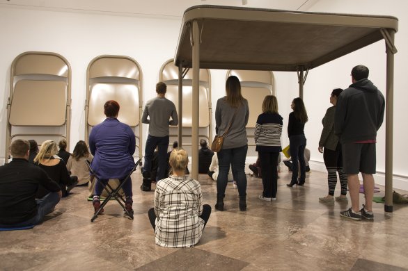 Guests meditate under and around Robert Therrien’s No title (folding table and chairs, beige), 2006