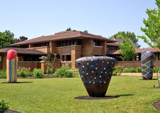 Three large ceramic sculptures in front of a brick house