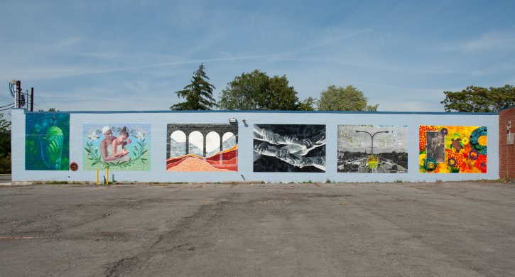 A long white wall with six colorful murals on it