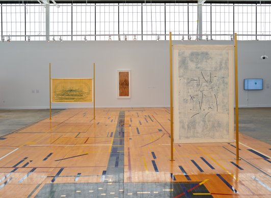 A wooden gym floor with two paneled works hanging above it