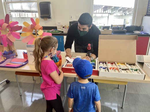 A man helping two children pick out art supplies