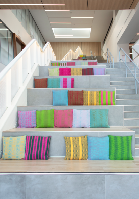 Multi-colored pillows adorning gray, concrete steps of a bright, indoor space
