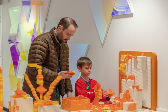 A man and his young son playing with orange legos