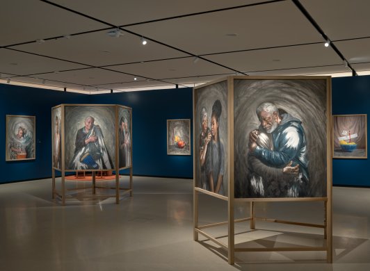 Installation view of oil painting portraits in two large wooden 'totems' and on dark blue walls