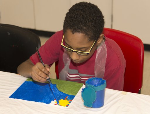 A young boy painting in the classroom