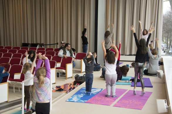 Kids and caregivers doing yoga in the Auditorium