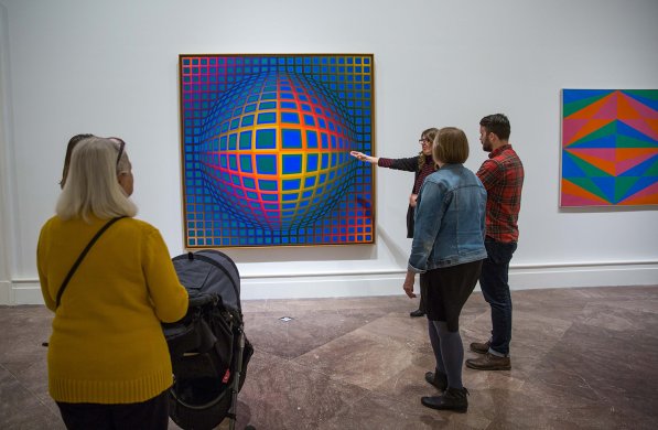 Several adults looking at Victor Vasarely's Op art painting Vega-nor
