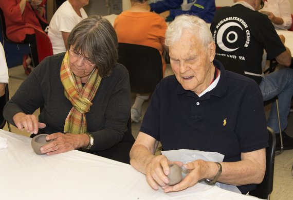 An older woman and an older man sculpting with clay in the classroom