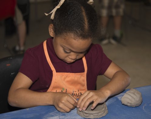 A young girl sculpting with clay in the classroom