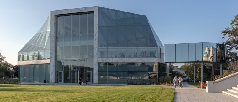 Glass museum building with a large front lawn