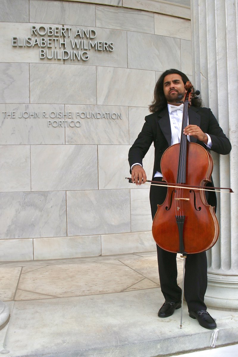 A man in a tuxedo posing with a cello