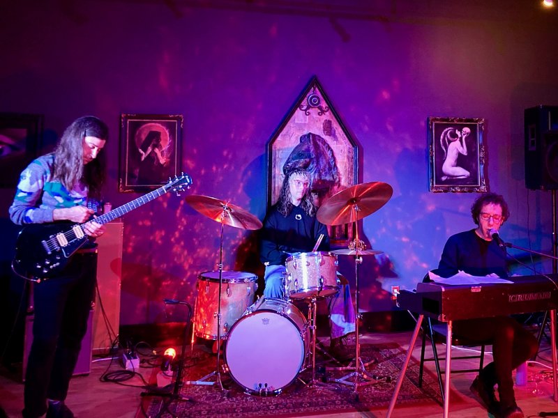 A band playing on a stage in dark purple and red lighting