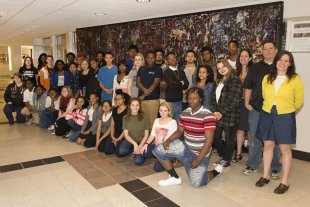 Photograph of students and teachers standing in front of large mural
