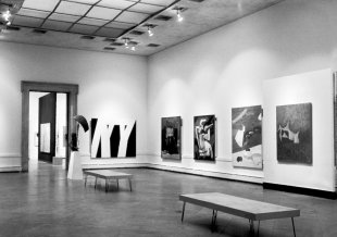 A black and white photograph of paintings hanging on two walls