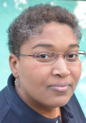A headshot of a black woman with short hair and glasses