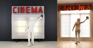 A person dressed all in white placing a black letter R on a lit sign, with the word &quot;CINEMA&quot; in red letters above it