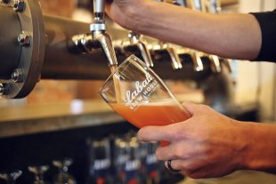 Hands pouring beer into a glass from a keg tap