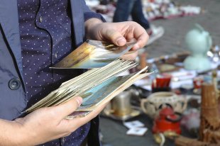 A close-up photograph of hands holding a stack of postcards