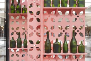 Green glass bottles on an elaborate pink shelving unit