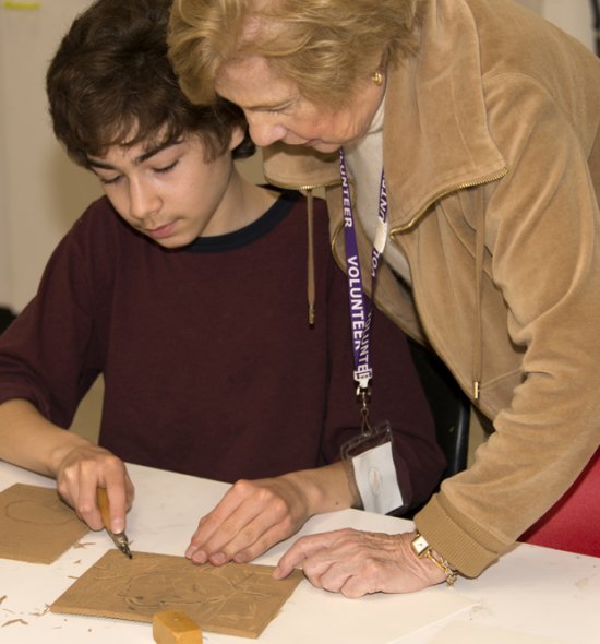 A volunteer helps a student during an art class