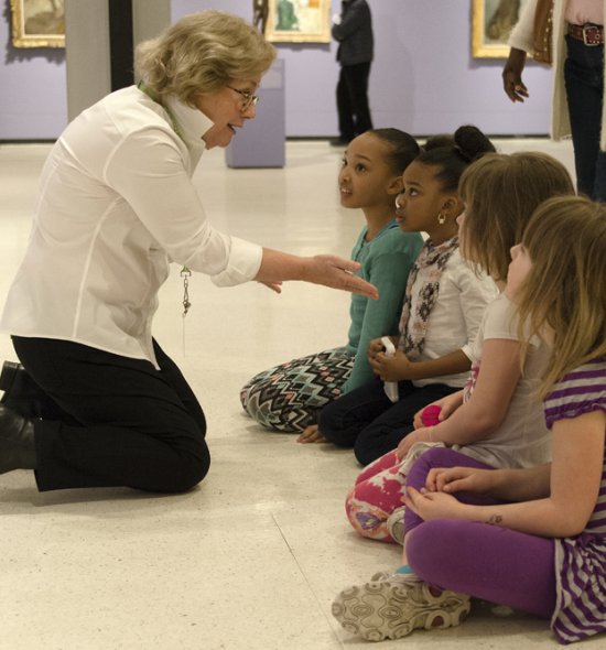 A docent sits and talks with students in the museum