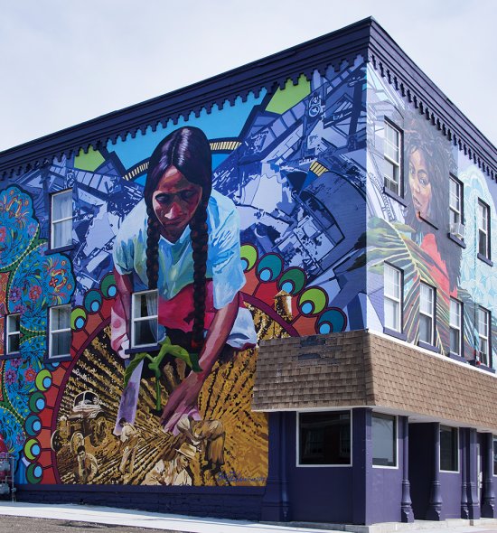 A large mural spanning two sides of a building featuring three Latinx women