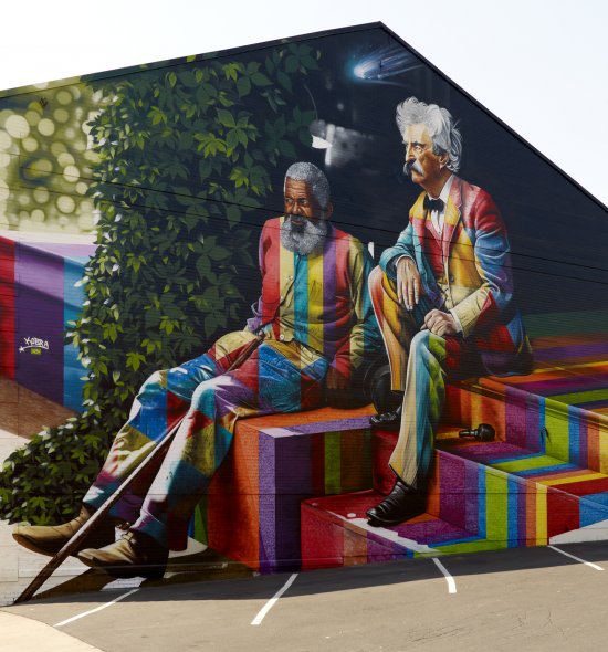 A large mural featuring an African American man and a white man sitting on the steps next to each other