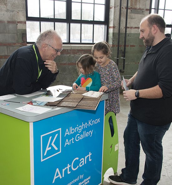 Two men and two young girls looking at materials on a cart