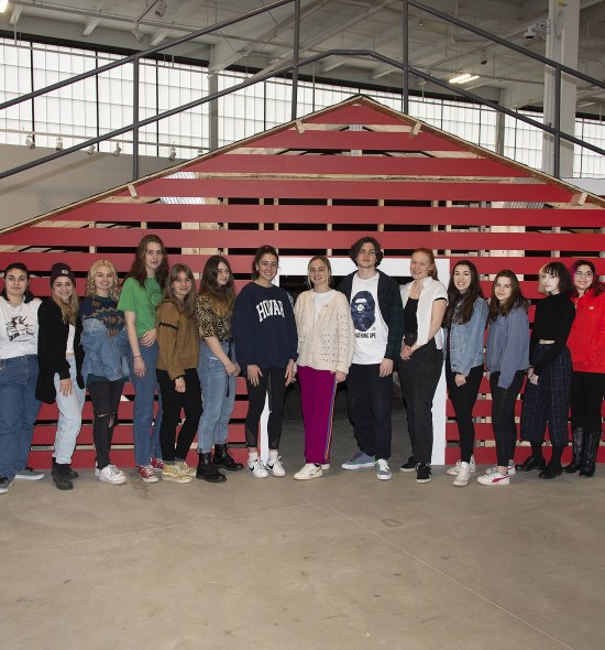 A group of teens standing in front of a rooftop built inside a large room