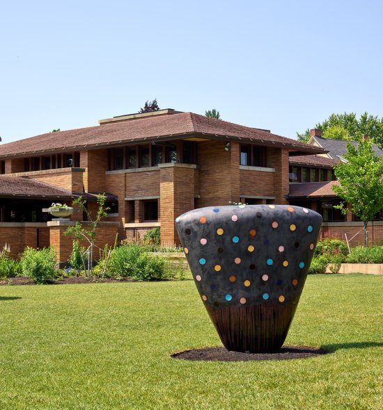 Three large ceramic sculptures in front of a brick house