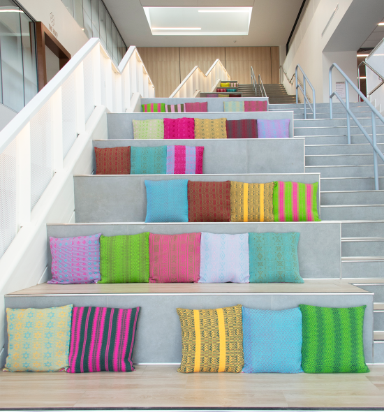 Multi-colored pillows adorning gray, concrete steps of a bright, indoor space