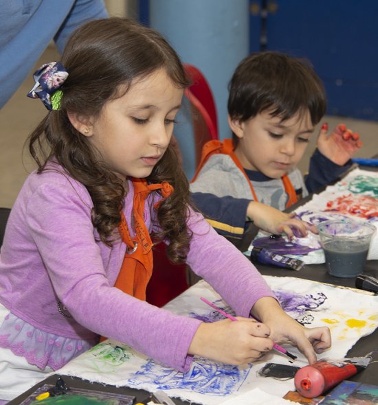 Two young children painting on fabric
